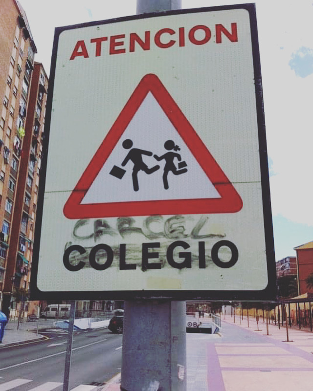 Señal que advierte a los conductores de la presencia de un colegio donde se ha tachado la palabra COLEGIO y se ha escrito encima CÁRCEL