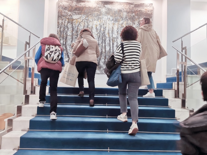Foto donde se ve a tres mujeres y un adolescente, de espaldas todas ellas, ascendiendo por unas escaleras.